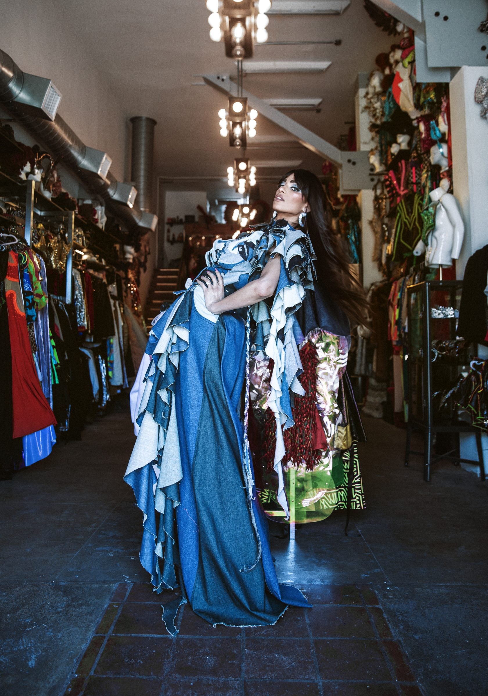 A model in a layered denim gown standing between the costume rails at The Archive Hollywood showroom